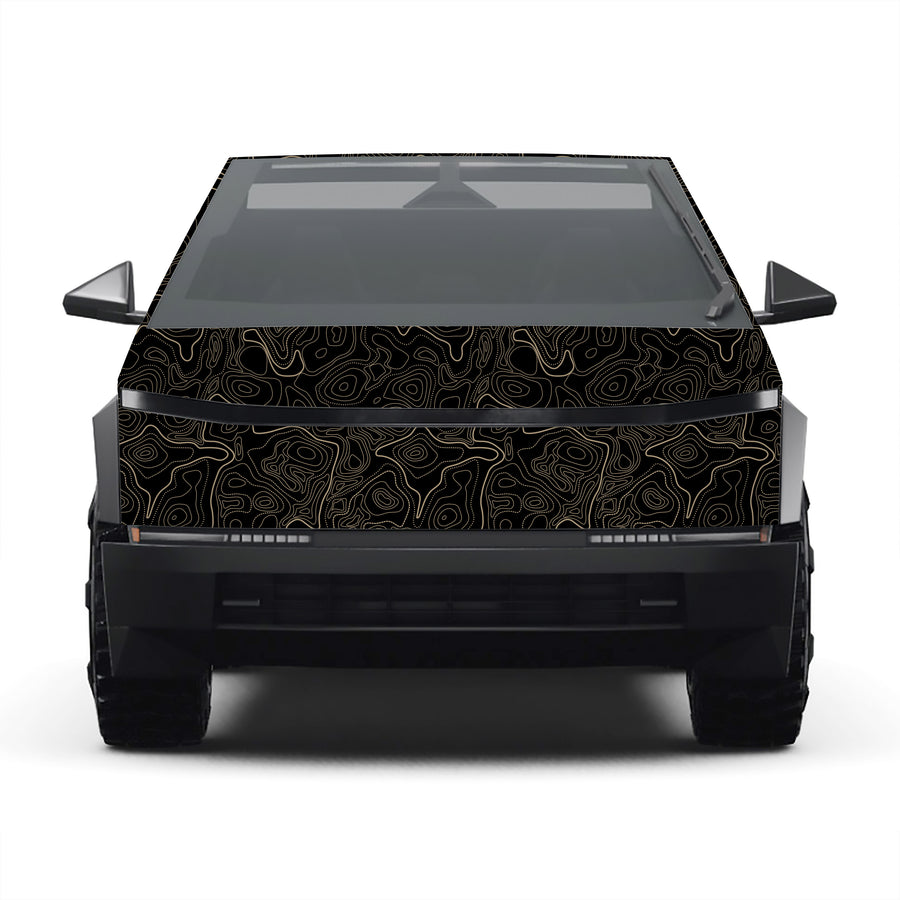 A side profile view of a Cybertruck-style pickup truck with a black wrap featuring a gold topographic contour line pattern, set against a plain white background.