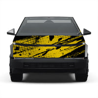 A front-facing view of a black electric vehicle with a bold yellow and black abstract brushstroke and dot pattern wrap on the hood, shown against a plain white background.